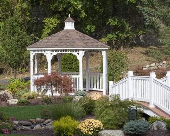 White octagonal vinyl gazebo in a backyard garden.