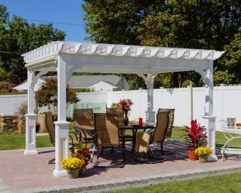 Traditional white vinyl pergola on a stone backyard patio.