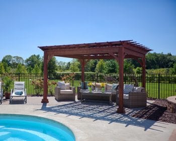 Traditional mahogany stain wood pergola on a patio by the pool.