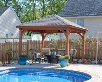 Traditional canyon brown stained wood pavilion with a gray roof next to a pool.