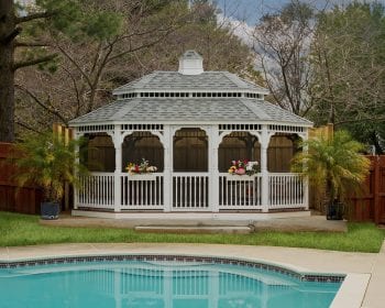 Oval white vinyl gazebo with screens and a pagoda roof by the pool.
