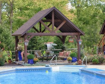 Dark Alpine cedar wood pavilion on a patio by the pool.