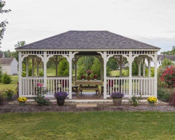 Country style rectangular almond vinyl gazebo in a backyard.