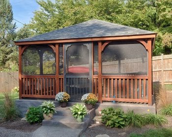 Brown dutch style wood gazebo with screens in a backyard.