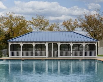 Country style white vinyl gazebo with a blue roof and screens on a patio by the pool.