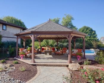 Octagonal dutch style gazebo with no bottom or railings on a stone patio by the pool.
