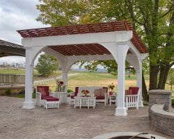 Vinyl Santa Fe style pergola with a brown top and white columns on a stone patio.