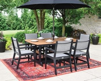 Black and gray Mayhew outdoor table set on a patio surrounded by trees.