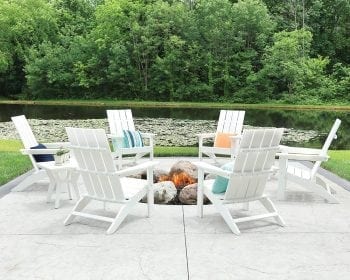 White Mayhew adirondack chair set around a fire pit by a lake.