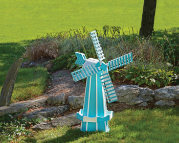 Aruba Blue & White Windmill in a lawn by a small rock wall.